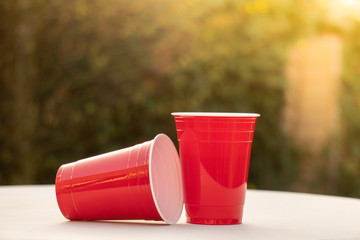 Plastic red solo drinking cups for beer pong or drinking games with green background on a white...