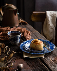 Homemade cinnamon cut roll bun on vintage blue plate with spoon on wooden rustic table