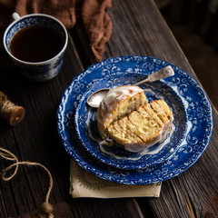 Homemade cinnamon cut roll bun on vintage blue plate with spoon on wooden rustic table