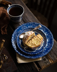 Homemade cinnamon cut roll bun on vintage blue plate with spoon on wooden rustic table