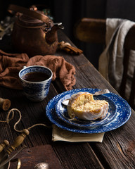 Homemade cinnamon cut roll bun on vintage blue plate with spoon on wooden rustic table