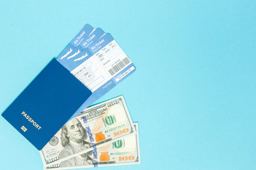 Tickets for plane and passport, dollars with model of plane on blue background. Copy space for text.