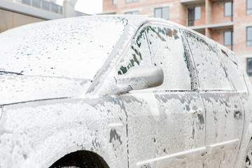 Car wash with foam in car wash station. Carwash. Washing machine at the station. Car washing concept. Car in foam