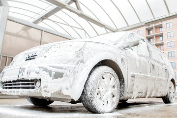 Car wash with foam in car wash station. Carwash. Washing machine at the station. Car washing...