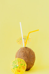 Fresh Coconut cocktail with a straws on yellow background, copy space