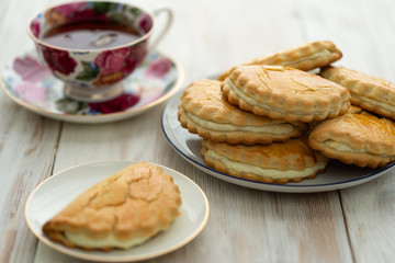 Freshly baked sochni on white plates served with tea. White wooden background, high resolution