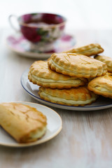 Freshly baked sochni on white plates served with tea. White wooden background, high resolution