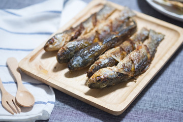 Fried mullet fish served on wood tray