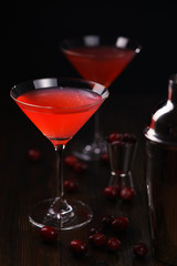 Cosmopolitan cocktail with cranberries, shaker and jigger. Dark wooden background, high resolution