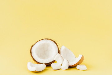 close up fresh coconut pieces isolated on a yellow background, tropical fruit concept, flat lay, pop art, copy space