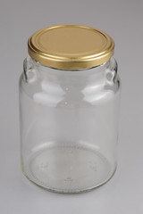 Empty glass jar with yellow, golden cover isolated on gray background