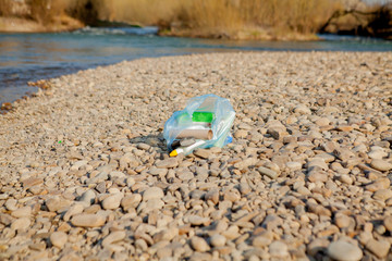Obraz premium River pollution near the shore, garbage near the river, plastic food waste, contributing to pollution