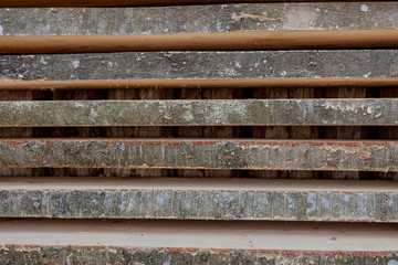 Folded wooden brown and gray planks in a sawmill. Piled alder boards as texture