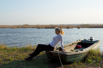 The Woman Sits On A Boat On The Lake Shore