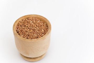 buckwheat groats in a wooden plate on a white background