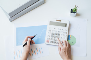 Businesswoman using a white calculator to calculate the value of business financial