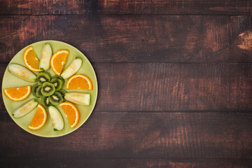Obraz na płótnie Canvas Kiwi apples and oranges on green plate
