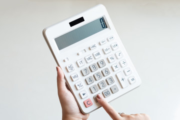 Businesswoman using a white calculator to calculate the value of business financial - obrazy, fototapety, plakaty