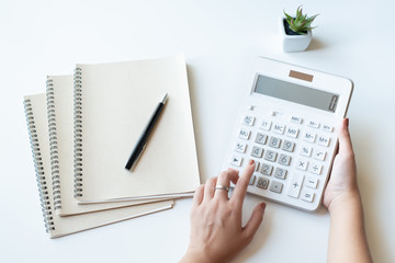 Businesswoman using a white calculator to calculate the value of business financial
