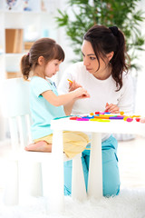 Mother helps a little daughter to sculpt figurines from plasticine. Children's creativity. Happy family