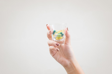 Young woman holding a small glass with multi-colored pills inside