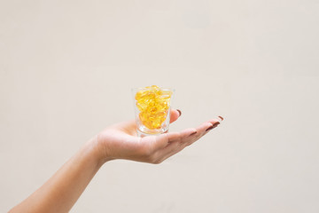 Young woman holding a small glass with yellow pills inside