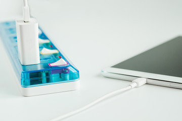 Digital tablet charging with extension socket on white background