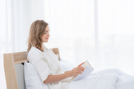 Beautiful woman reading a book on the bed in the morning