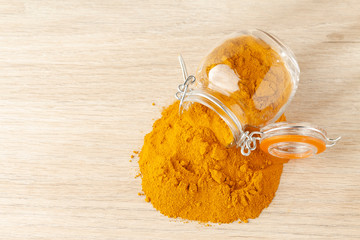 turmeric powder in glass bowl on wood
