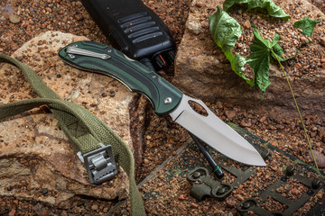 Obraz premium Folding knife and walkie-talkie are on the rocks