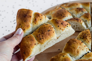 A hand holding a piece of Ramadan bread,pide on the other triangle pieces.
