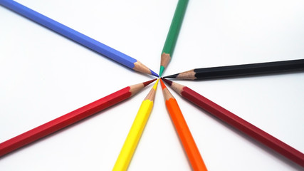 Closeup of color pencils pointing toward each others in circular layout.