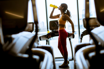 Fototapeta na wymiar Young women in yellow sport shirt are drinking water at the gym