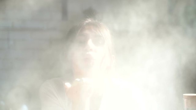 Portrait of young woman blowing flour from hand right to the camera. Doing air kiss. Smiling and looking at the camera. Slowmotion.