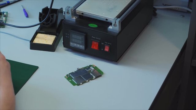 Service repair shop. Laptop charger maintenance and renovation. Worker hands soldering wires on disassembled broken damaged part