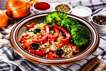 Groats with vegetables on wooden table