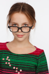 Portrait of 8-year-old girl in glasses and a sweater in a crimson and green stripes. Studio photo session