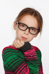 Portrait of 8-year-old girl in glasses and a sweater in a crimson and green stripes. Studio photo session