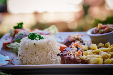 steak served in a restaurant dish with frites and rice