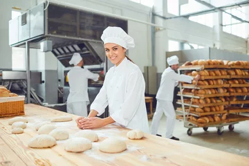 Fotobehang Een vrouwelijke bakker glimlacht met collega& 39 s bij een bakkerij. © Studio Romantic