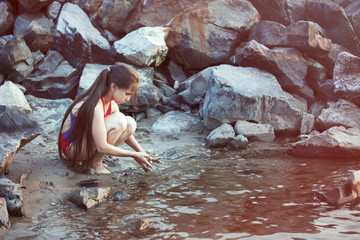Young cute girl sitting near water.
