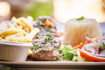 steak served in a restaurant dish with frites and rice