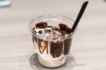 Gelato con cioccolato fuso in un bicchiere di plastica trasparente