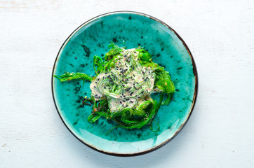 Green salad of seaweed in a plate. Top view. Free space for your text.