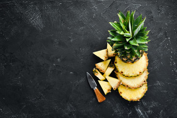 Sliced pineapple on a black background. Tropical Fruits. Top view. Free copy space.
