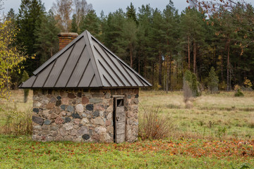 Old stone shed with new roof at a farm on a rainny day in Latvia rural area