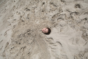little girl buried in the sand on the beach