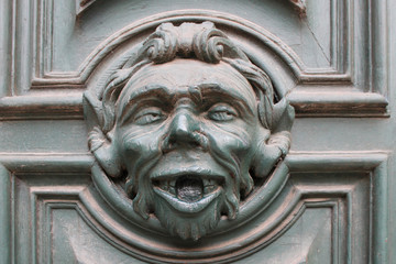 Relief head of a Satyr on an old wooden door in Venice, Italy