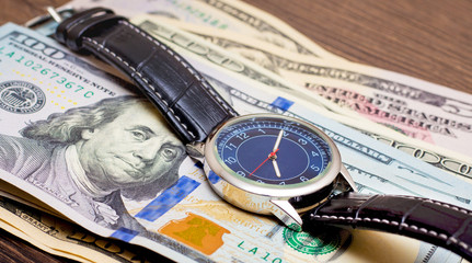 The watch is lying on dollars. Time to earn money. Time is money_