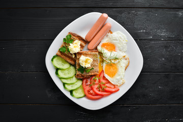 Breakfast: eggs, sausages and vegetables on the plate. Top view. Free space for your text. Rustic style.